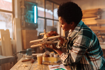 Cheerful female carpenter with toy product.