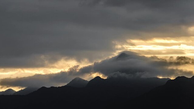 Majestic mountain peak silhouette at sunset surrounded by turbulent clouds