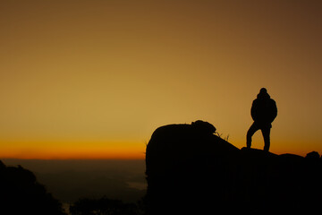 hiker watching the sunrise on top of the mountain