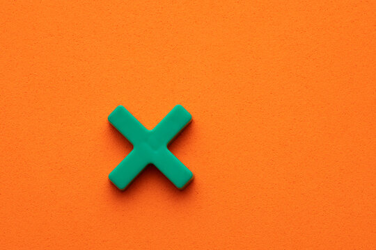 Green color math multiplication sign on orange foamy background