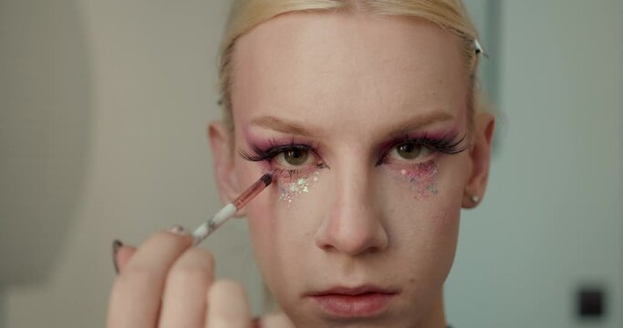 Transgender guy applying make up on eyes using a brush