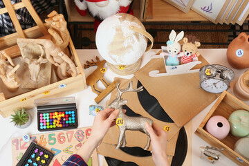 Woman holding toy deer near table with many different stuff, above view. Garage sale