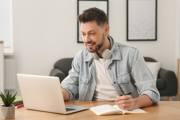 Naklejka premium Online translation course. Happy man near laptop at home