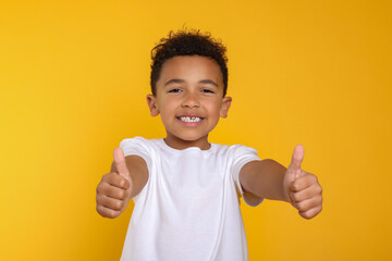 African-American boy showing thumbs up on yellow background
