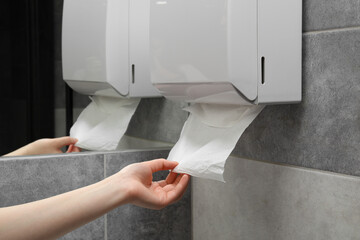 Woman taking new fresh paper towel from dispenser in bathroom, closeup - obrazy, fototapety, plakaty