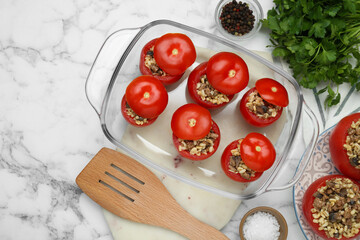 Fototapeta na wymiar Delicious stuffed tomatoes with minced beef, bulgur and mushrooms in glass baking dish on white marble table, flat lay