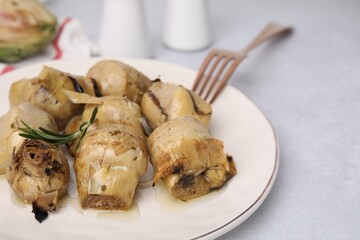 Delicious pickled artichokes with rosemary served on white table, closeup