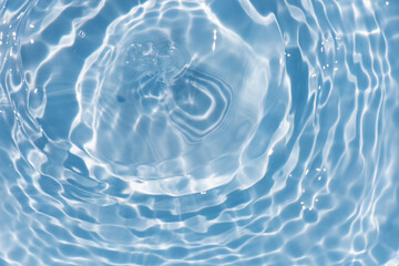 Blue water with ripples on the surface. Defocus blurred transparent blue colored clear calm water surface texture with splashes and bubbles. Water waves with shining pattern texture background.