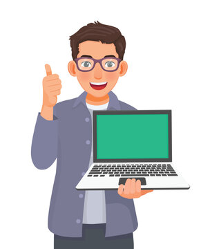 Young businessman with glasses holding laptop with blank screen for copy space showing thumb up