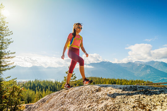 Hiking people. Woman hiker on mountain hike trail enjoying view wearing backpack and hiking clothing in beautiful blue sky nature landscape. Squamish hike, British Columbia, Canada.