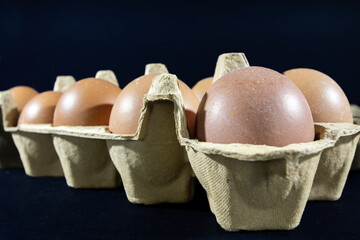 Studio shots of an isolated eggs box on a black background containing brown eggs, ra and organic,...