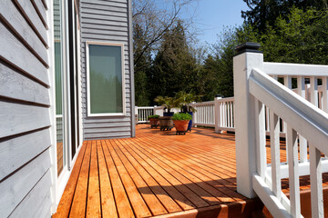 Freshly stained walk out home outdoor cedar wood deck with potted plants - obrazy, fototapety, plakaty
