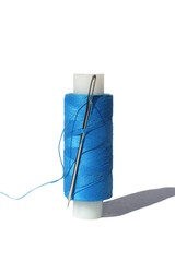 A spool of blue thread and a needle is on a white isolated background.
