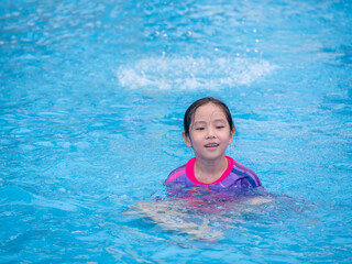 Little asian child girl play on the pool in summer