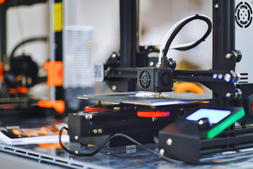 Modern 3D printer with computer chip controlled printing arm on table at school science club. 