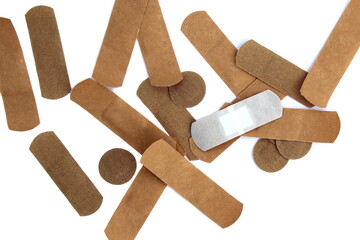 A pile of adhesive plasters lie on a white background.
