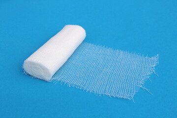 A white medical bandage lies on a blue background.	