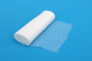 A white medical bandage lies on a blue background.	
