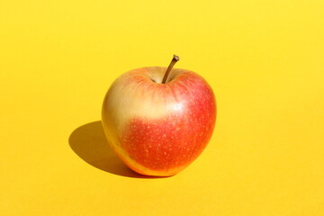 There is a red apple on a yellow background.