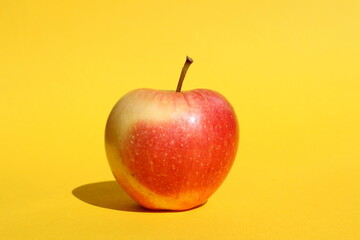There is a red apple on a yellow background.	