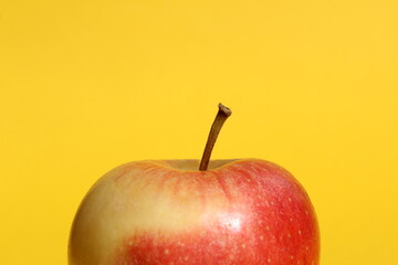 There is a red apple on a yellow background.