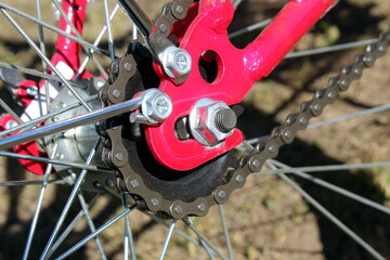 Wheel of a red new bicycle with a chain.