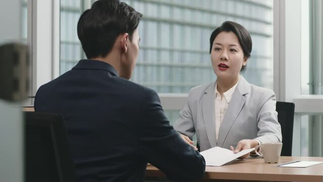 female asian supervisor reviewing performance with subordinate in office