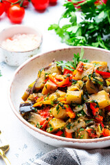 Vegetable stew, saute or caponata. Stewed eggplant with red paprika, tomatoes, garlic, onion, spices and herbs. White kitchen table background, top view