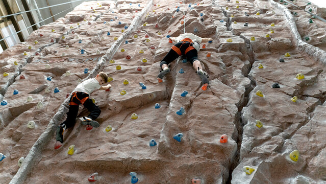 a boy and his mother climb a climbing wall