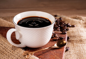 Fresh coffee. A coffee cup or mug lies on a wooden table with roasted coffee beans. Espresso mocha cappuccino barista, top view.