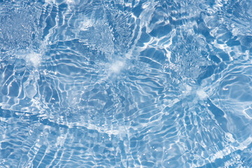 Blue water with ripples on the surface. Defocus blurred transparent blue colored clear calm water surface texture with splashes and bubbles. Water waves with shining pattern texture background.