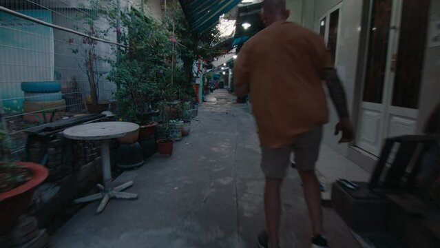 Parkourist in sportswear walking along narrow street in old town and performing epic side flip stunt. Back shot