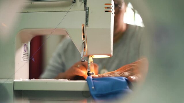 A scene or shot of an adult woman attempting to sew a cloth or garment on an old sewing machine. Concer machine concept. Person working in her sewing business