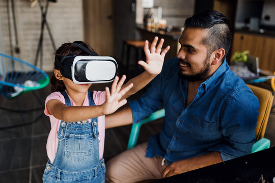 Latin father playing virtual reality game with his daughter at home in Mexico Latin America, hispanic family