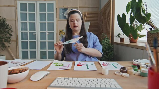 Modern young woman with Down syndrome working as online teacher of English for children