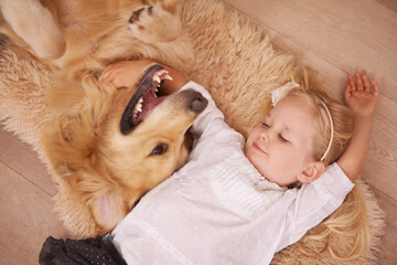 Girl, dog and hug together on floor in living room and golden retriever, kid and relaxing with pet...