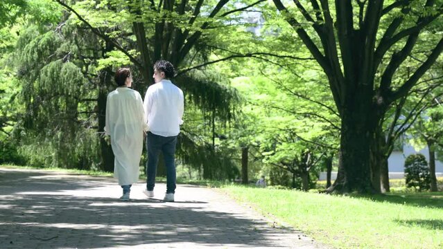 Animation of a married couple walking hand in hand amidst fresh greenery, gazing at each other, from the faceless