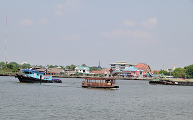 BANGKOK, THAILAND - May 6, 2023 : A small boat is dragging a sand barge through the Chao Phraya...