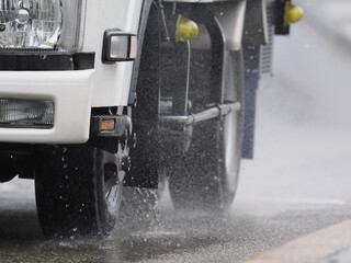 雨に日に水しぶきを上げて走ってくるトラック