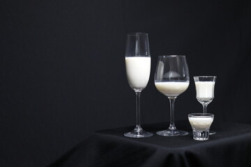 Milch in Gläsern vor schwarzem Hintergrund