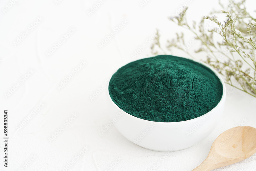 Wall mural spirulina powder in a bowl background. food spirulina powder food on white table background. spirulina powder