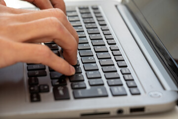 ノートパソコンのキーボードを打つ