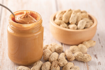 Peanut butter in jar and wood bowl on table