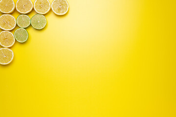 Fresh, Fruity and juicy fruit concept. View from top. Freshly cut slices of lemons and limes on the left upper corner of the image on a yellow background.