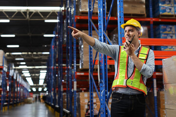 Caucasian warehouse worker man with hardhat and reflective jackets using tablet, walkie talkie...