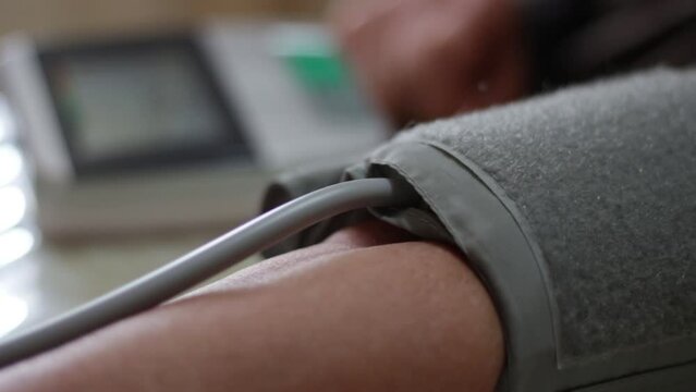 Close-up of blood pressure monitor inflating. Blood pressure gauge on the arm of the elderly woman. Using digital tonometer machine at home. Healthcare, disease treatment concept.

