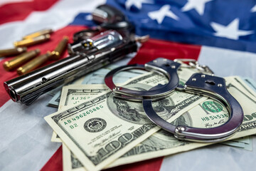 money gun with handcuffs  casings against the background of an American flag lying carelessly