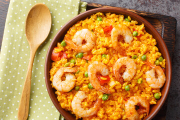 Yellow rice with shrimp with some addition of vegetables and spices close-up in a bowl on the table. horizontal top view from above