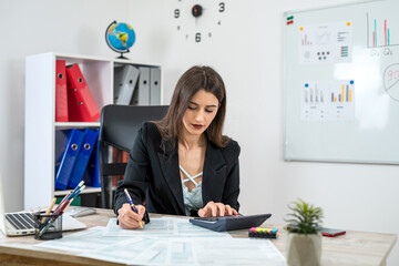 Caucasian businesswoman in suit filling 1040 form of individual income tax return at modern office