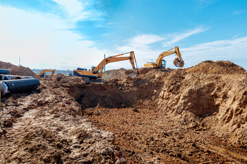 Two Excavator are digging soil in the construction site on sky background,with white fluffy cloud